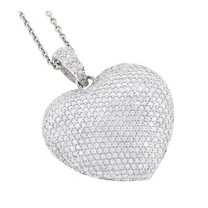 Silver heart-shaped pendant encrusted with numerous small diamonds in a micro pave setting, hanging from a silver chain.