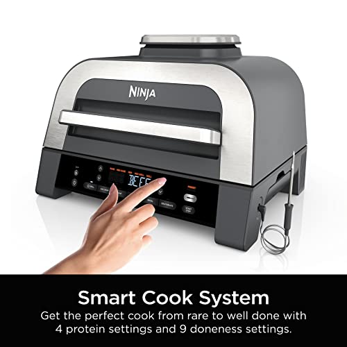 A Ninja Foodi XL Cooker with a digital display and a person's hand touching the control panel. Features include a Smart Cook System with 4 protein and 9 doneness settings.