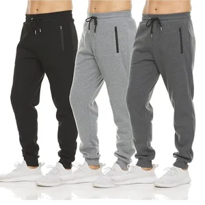 Three pairs of men's jogger sweatpants in black, light gray, and dark gray. Each pair features a drawstring waistband, zippered side pockets, and is paired with white sneakers.