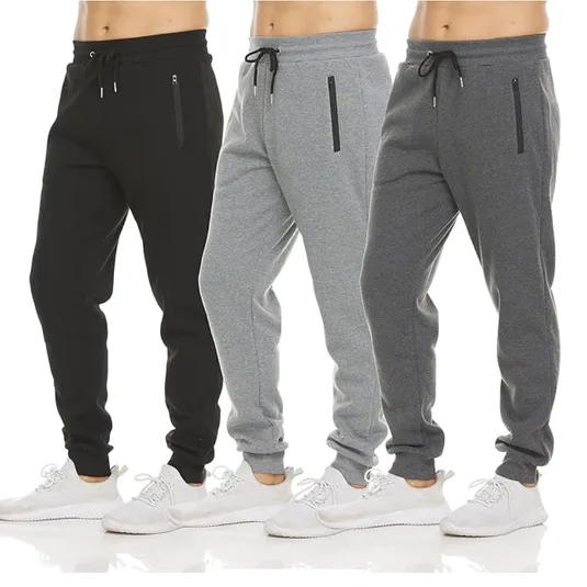Three pairs of men's jogger sweatpants in black, light gray, and dark gray. Each pair features a drawstring waistband, zippered side pockets, and is paired with white sneakers.