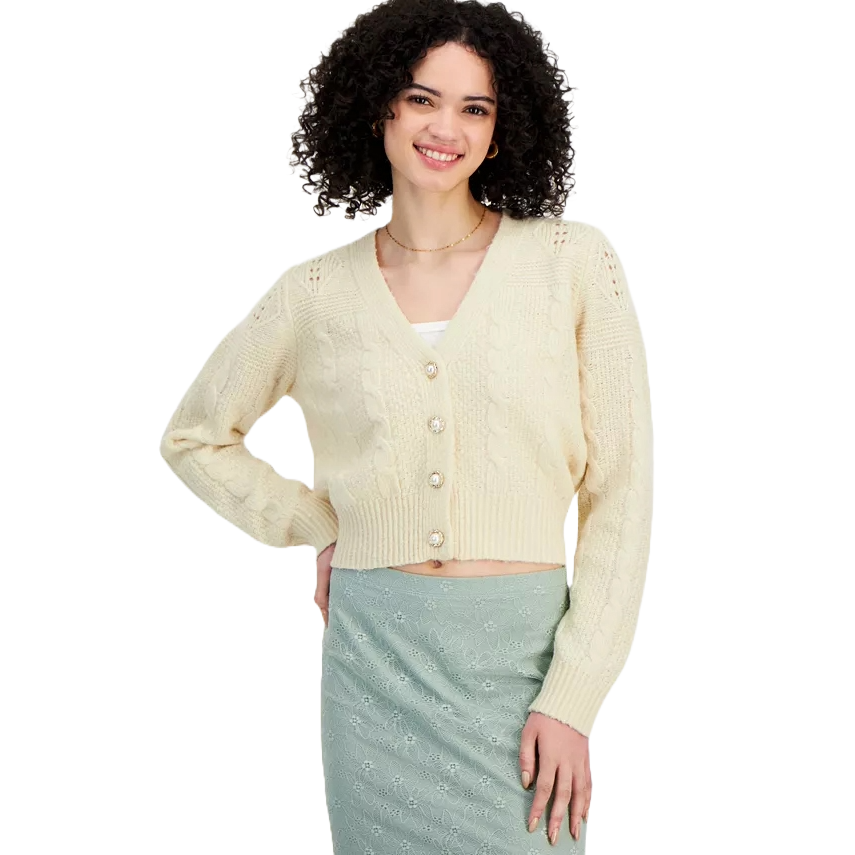 The Sugar Moon Bling-Button Cardigan is a cream-colored, cropped knit sweater with a V-neckline and cable pattern. It features decorative buttons and long sleeves.