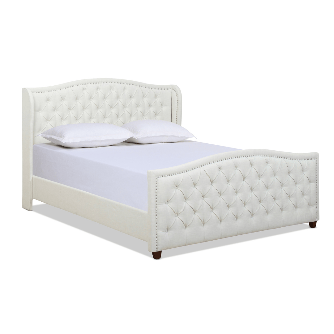 A white upholstered bed frame with a tufted headboard and footboard, featuring nailhead trim and wooden legs, includes a mattress with two pillows.
