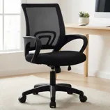 Black mesh office chair with armrests, adjustable height, and swivel base, placed in a bright room next to a simple wooden desk.