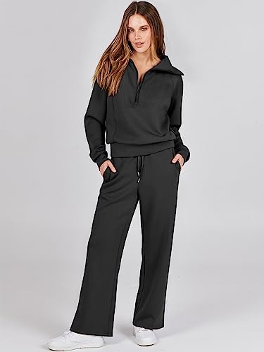 A woman is wearing a two-piece lounge set consisting of a cropped black hoodie with a half-zip front and matching wide-leg pants with a drawstring waist.