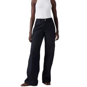 A person is wearing high-waisted, wide-leg black pants paired with a white sleeveless top and sandals.