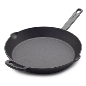Cast iron skillet with a long handle and an additional helper handle, featuring dual pour spouts.