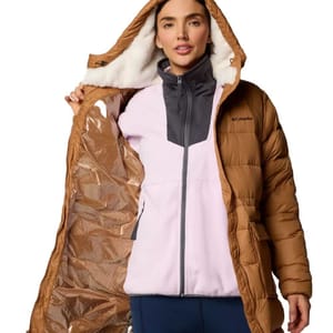 A woman models a brown Columbia puffer jacket with a warm hood and a soft light pink and grey fleece jacket underneath.