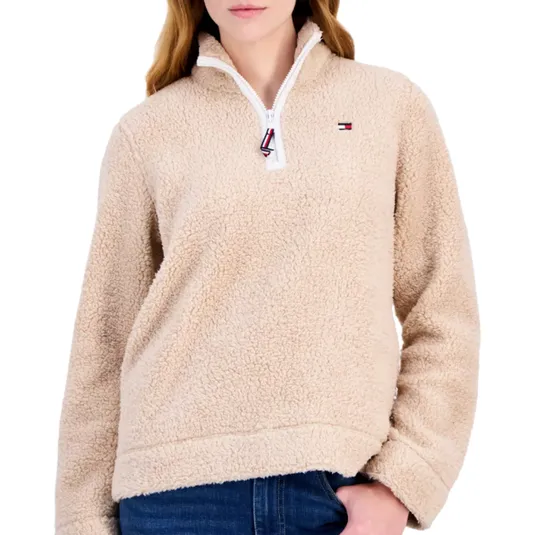 Beige sherpa fleece pullover with a quarter-zip closure and a small embroidered logo on the chest, paired with blue jeans.