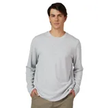 A man is wearing a light gray long-sleeve crew neck shirt and khaki pants, with hands in pockets, set against a plain gray background.