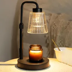 A black lamp with a glass shade is shown warming a lit candle in a brown jar on a round base, next to a white bowl with a spoon.