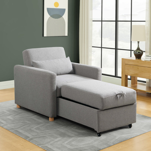 A gray chaise lounge with an attached ottoman and two accent pillows against a window.