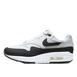 Nike Air Max 1 features a white and light gray upper with a black mudguard, white midsole, and visible Air unit. It has a black Swoosh and a lace-up closure.