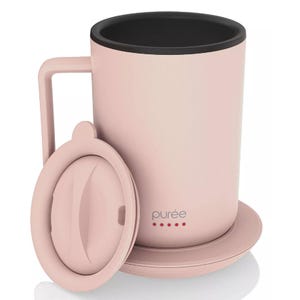 A pink mug with a handle and lid, labeled \“purée\“ with red dots, featuring a black interior.