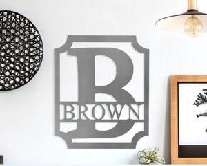 Wall decal with the letter \“B\“ inside a shield silhouette, featuring the word \“BROWN\“ below, displayed on a home wall.