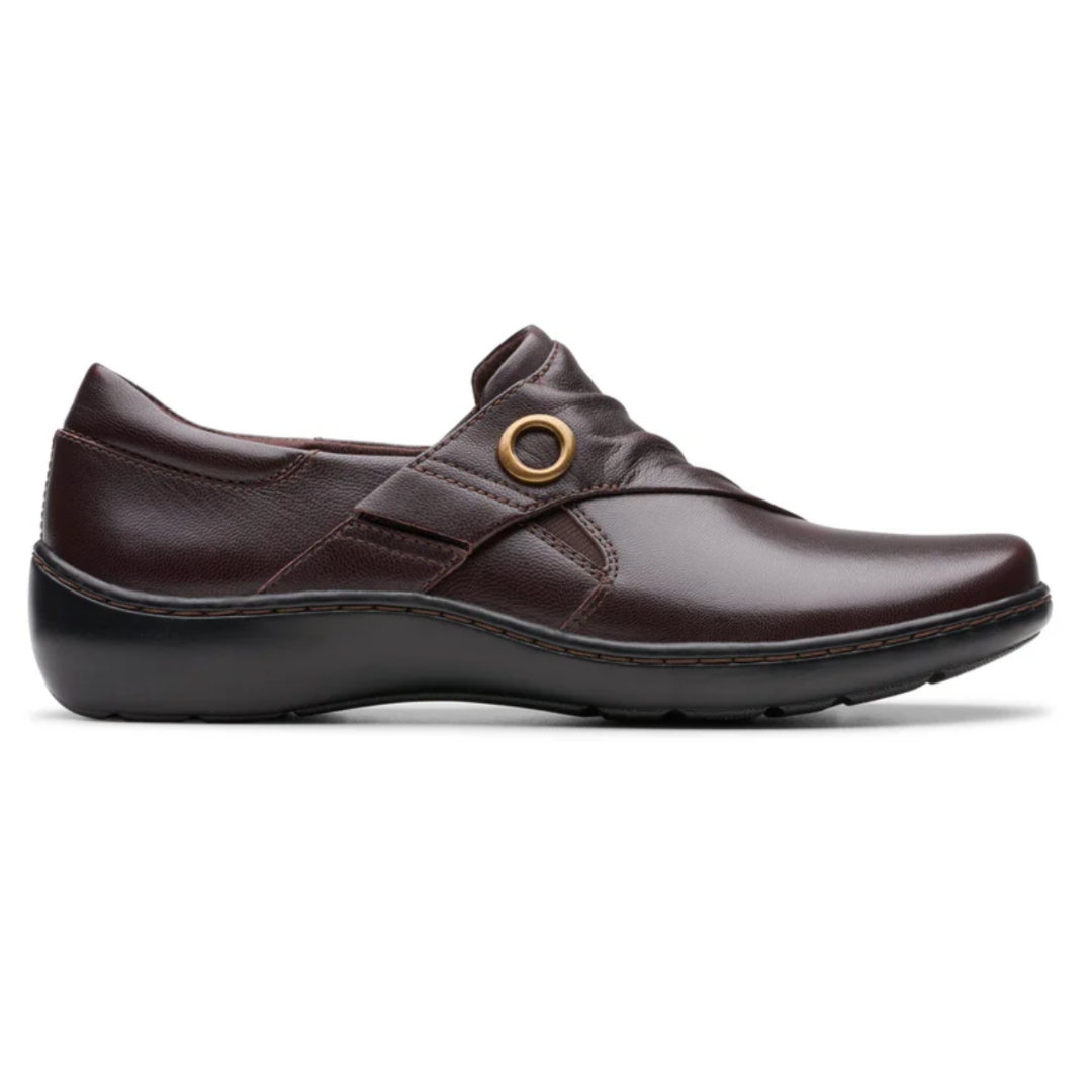 Dark brown leather slip-on shoe with a low wedge heel and decorative metal ring detail on the side.