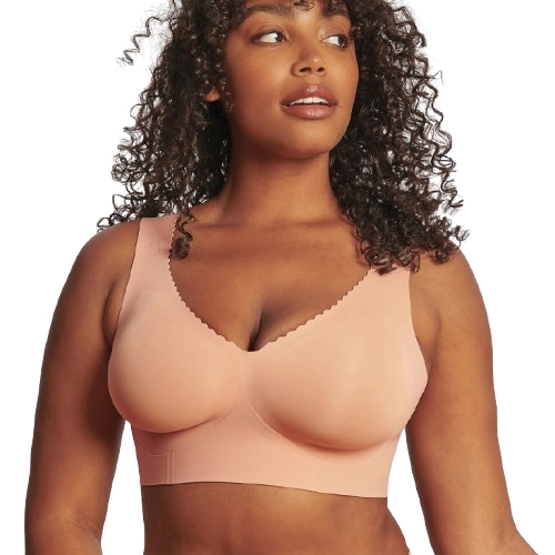 A woman is wearing a peach-colored seamless bra with wide straps and scalloped edges.