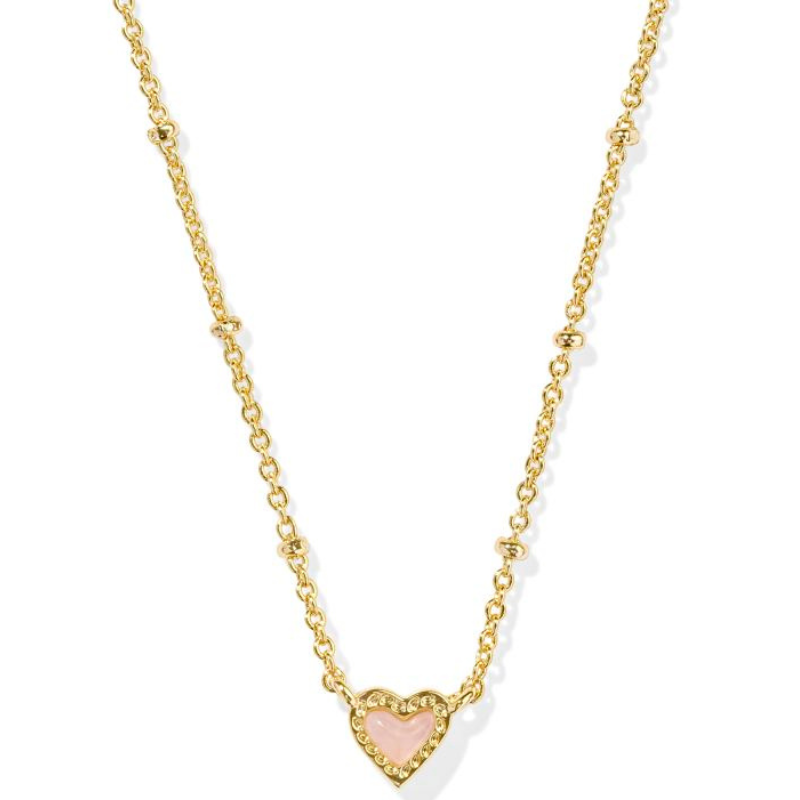 Kendra Scott Mini Ari Heart Necklace features a gold chain with small round accents and a pink heart-shaped pendant bordered by gold.