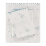 A set of bed sheets with a light blue floral pattern on a white background, featuring scalloped blue edges.