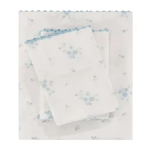A set of bed sheets with a light blue floral pattern on a white background, featuring scalloped blue edges.
