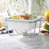 White ceramic chafing dish with a lid placed on a metal stand, kept warm by a tealight candle underneath.
