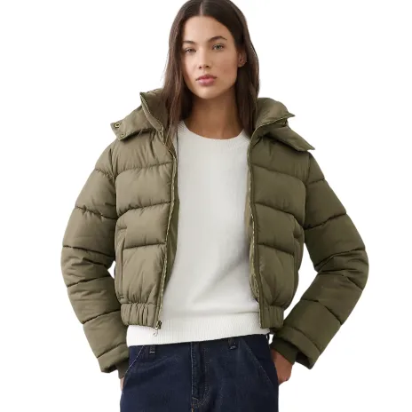 A person is wearing a khaki green puffer jacket over a white sweater paired with dark jeans.