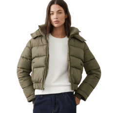 A person is wearing a khaki green puffer jacket over a white sweater paired with dark jeans.