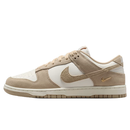A beige and white Nike Dunk Low sneaker featuring a suede and leather combination with a gold mini Swoosh on the heel.