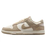A beige and white Nike Dunk Low sneaker featuring a suede and leather combination with a gold mini Swoosh on the heel.