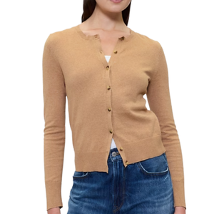 A woman is wearing a camel-colored, long-sleeve cardigan with button closure, paired with blue jeans.