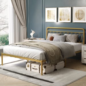Golden steel bed frame with curved headboard and footboard, complemented by white and gray bedding and storage suitcases underneath.