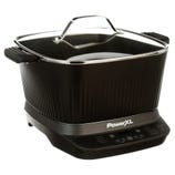 PowerXL electric cooker with a black body, ribbed sides, handles, and a glass lid. Features a digital control panel for various cooking functions.