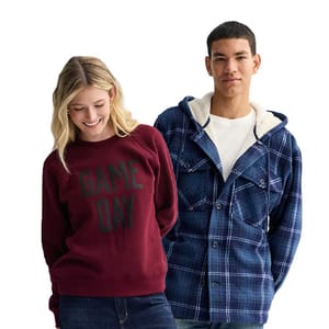A woman wears a maroon \“GAME DAY\“ sweater and blue jeans, while a man wears a blue plaid hooded jacket over a white shirt.