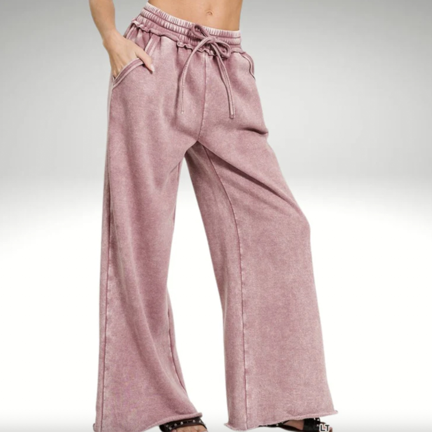 A person is wearing light purple, wide-leg drawstring sweatpants.