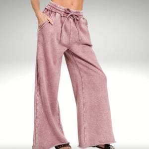 A person is wearing light purple, wide-leg drawstring sweatpants.