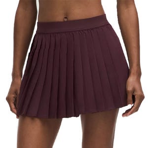 A pleated mini skirt in a deep burgundy color, featuring a high waistband for a sporty and stylish look.