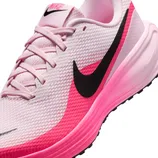 A pink and white Nike running shoe featuring a bold black swoosh and laces, with a gradient pink sole.