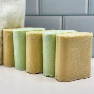 5pk Amish Organic Bar Soap features five blocks in shades of green and beige. The soap has a rustic appearance with a natural, textured finish, ideal for those seeking traditional, handmade toiletries.