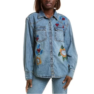 A blue denim shirt from Free People featuring floral embroidery on the chest and sleeves, two front pockets, and a button-up front.