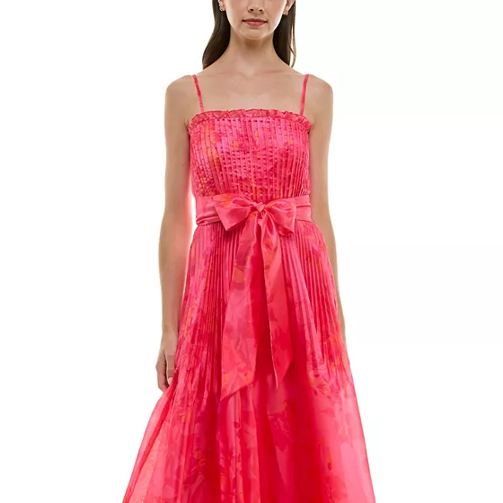 A pink spaghetti strap dress with a ruched bodice and a large bow at the waist, featuring a semi-transparent, flowing skirt.