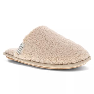 A cozy, beige slip-on slipper with a fluffy, textured surface and a flat sole.
