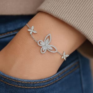 A bracelet featuring a silver chain with three butterfly designs, including a larger central butterfly flanked by two smaller ones, all adorned with sparkling details.