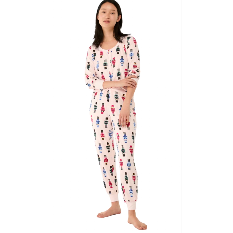 Women's Kate Spade pajamas featuring a light pink background with colorful nutcracker prints. The set includes a long-sleeve top and matching pants, both with ribbed cuffs.