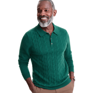A man is wearing a green cable-knit sweater with a polo collar and buttons, paired with brown pants.