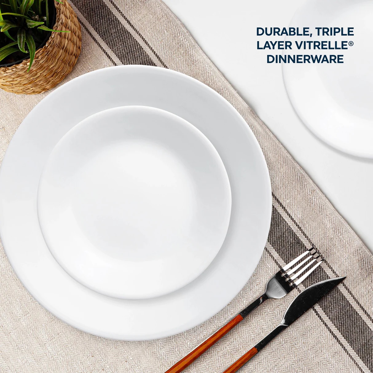 White triple-layer Vitrelle dinnerware set comprising of large and small round plates with a fork and knife on a striped napkin.