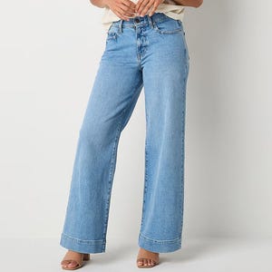 A pair of light blue high-waisted wide-leg jeans paired with open-toed sandals.