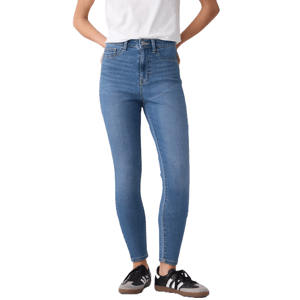 High-rise, medium blue jeggings with a stretchy fit, featuring a button and zip closure. Worn with a white top and black sneakers with white stripes.