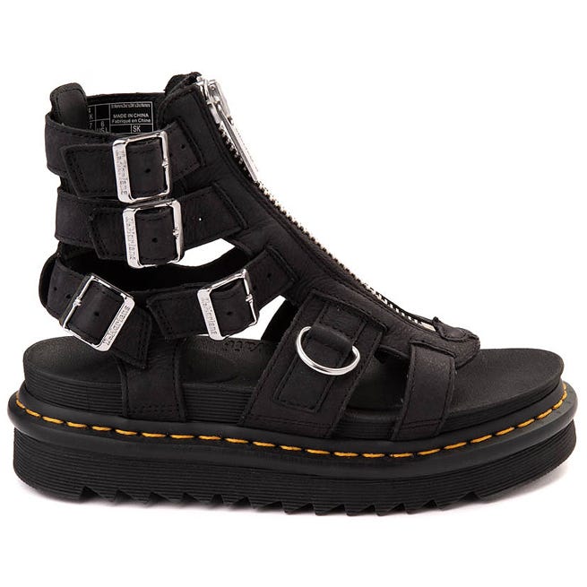 Black gladiator-style sandal with a zip closure, buckle straps, and a thick platform sole featuring yellow stitching.