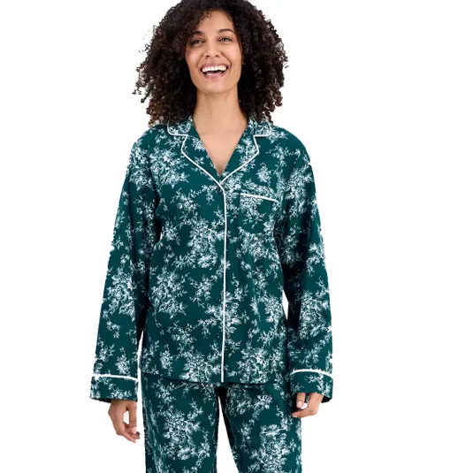 A person is wearing a dark green pajama set with a white floral pattern and white piping on the collar, cuffs, and pocket.