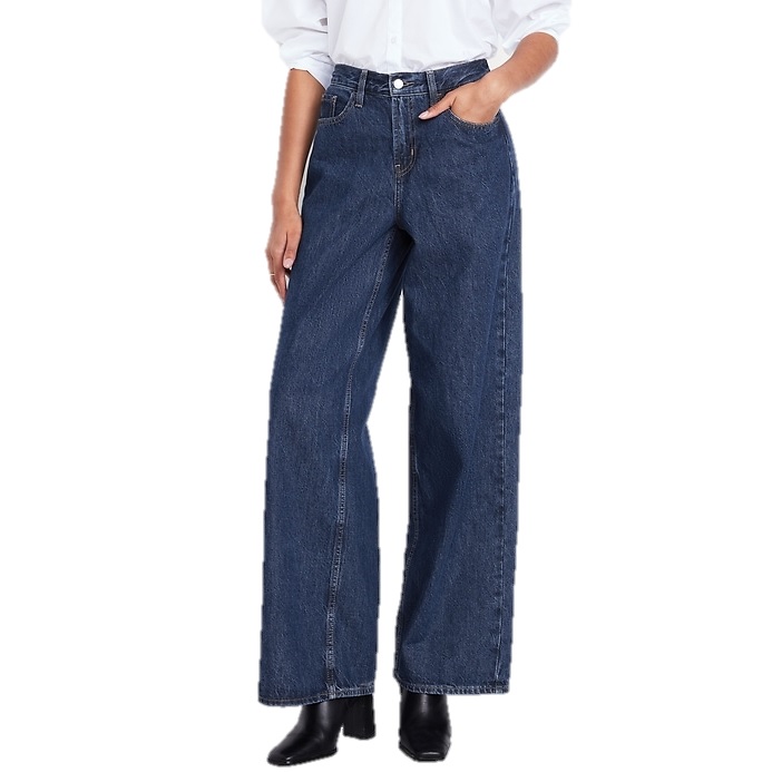 A person is wearing dark blue, wide-leg jeans paired with a white shirt and black boots.