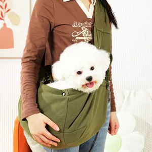 A person carries a fluffy white dog in a green pet sling bag. The bag is worn crossbody, allowing the dog to comfortably sit and peek out.